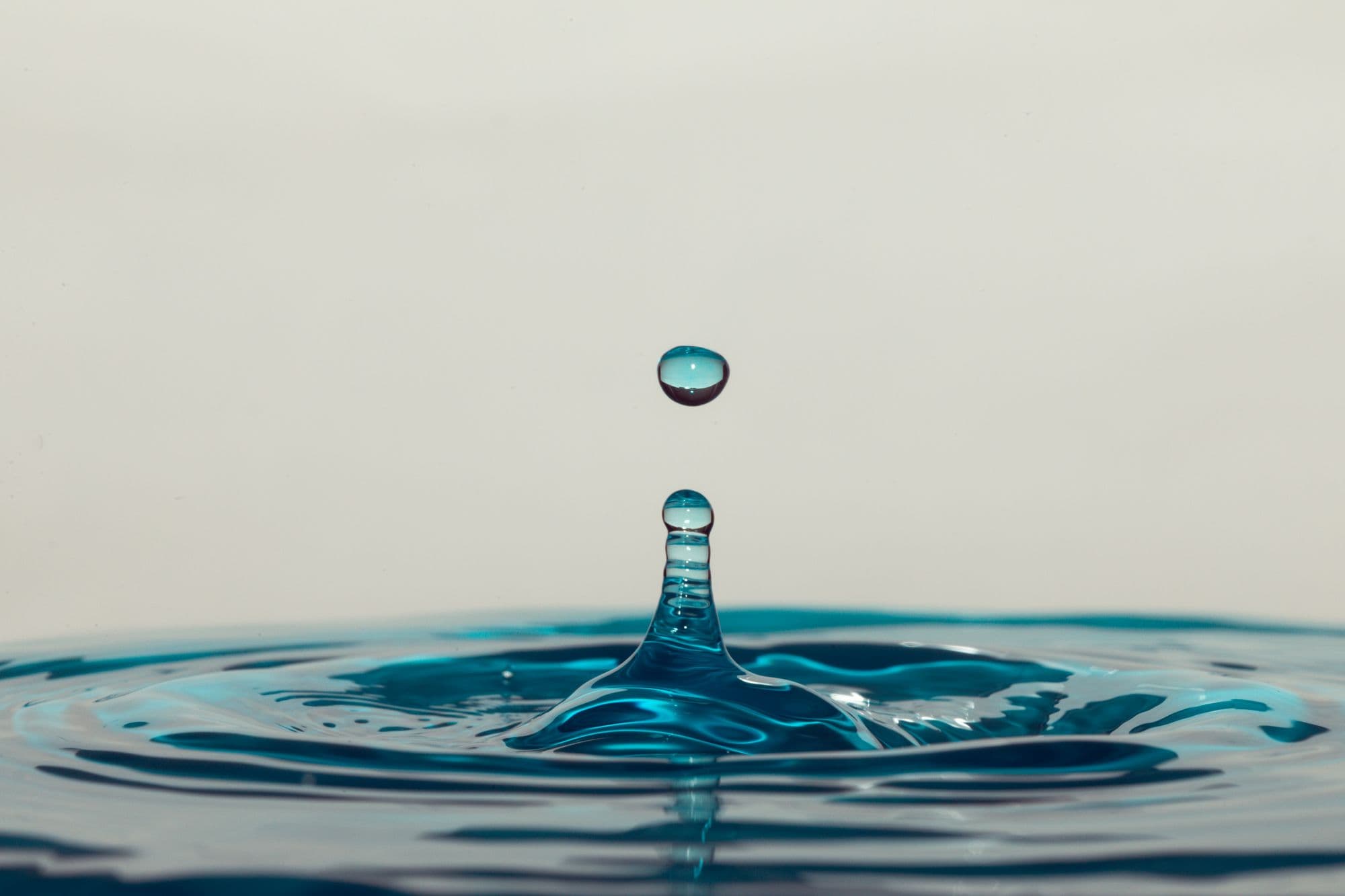 Wassertropfen springt aus einer ruhigen Wasseroberfläche